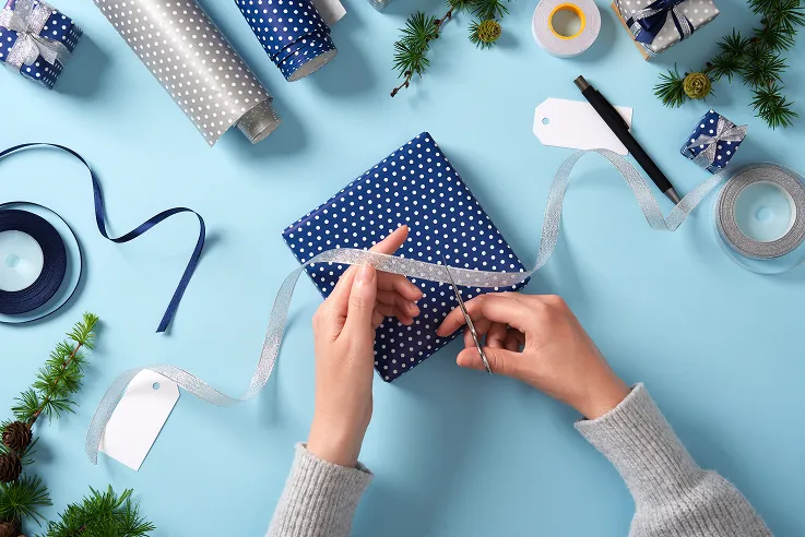 En person som klipper et gavebånd over en gave