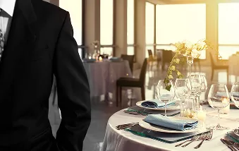 En person i dress som står foran ett pent pyntet bord