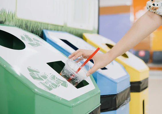 En person som kildesorterer en plastkopp